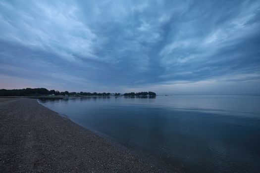 Peaceful view of Stamford shoreline with calm ocean waters and dramatic sky.