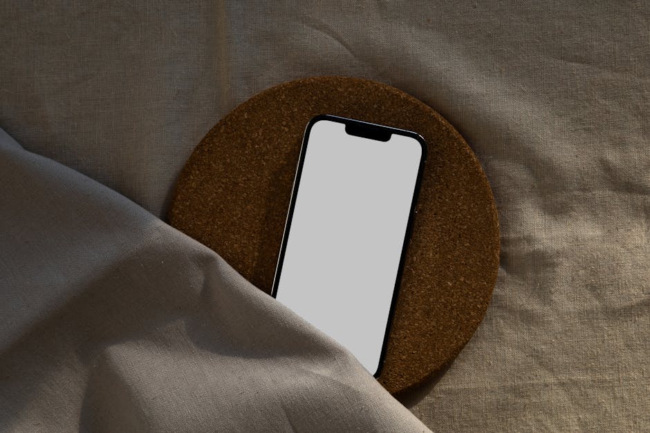 What Fitbit Premium Sleep Profile Animal Types Reveal About Your Rest A smartphone with a blank screen on a circular cork surface over a fabric background.