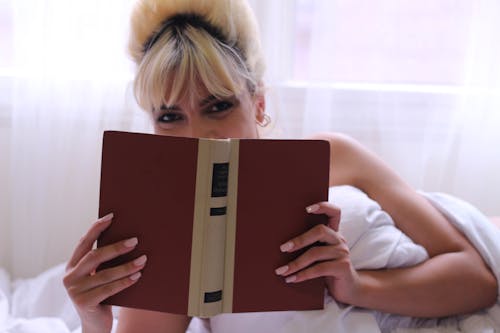 Wanita Menutupi Wajah Dengan Buku Coklat
