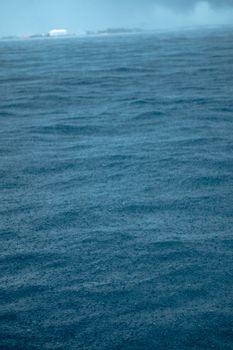 A captivating ocean view under a rainy sky, showcasing dynamic waves and a distant horizon.