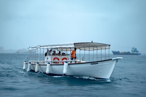 Free A traditional white boat navigates calm blue ocean waters, offering a serene seafaring experience. Stock Photo