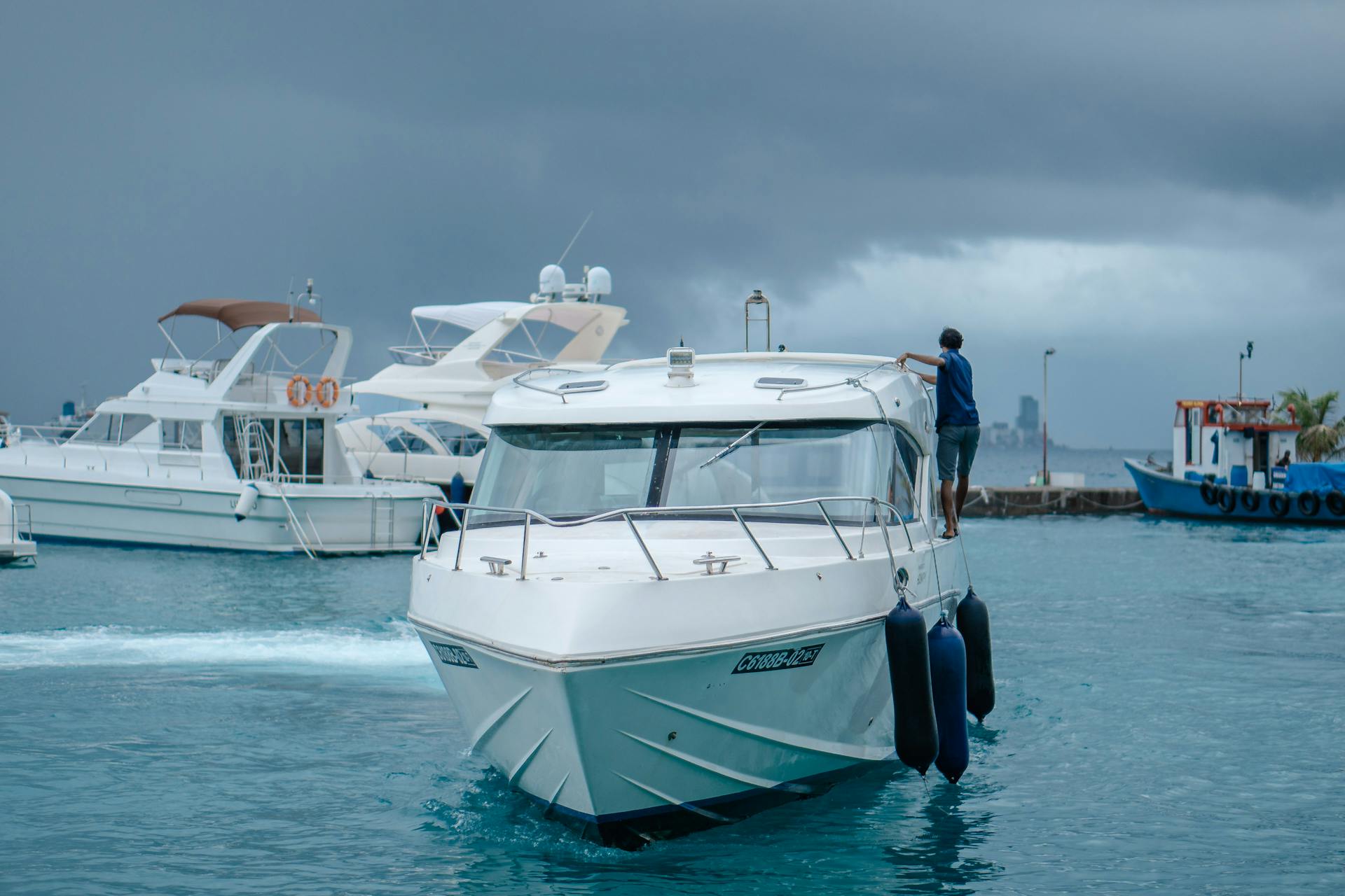 White luxury yacht in a serene ocean marina with storm clouds brewing.