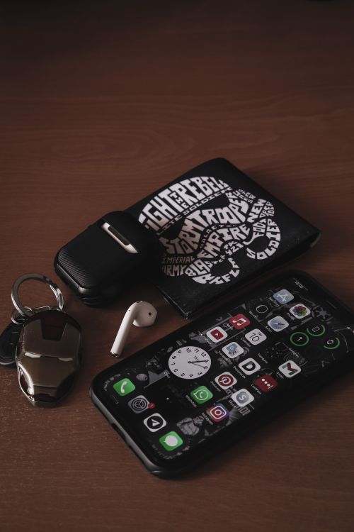 Free Modern flat lay showcasing a smartphone, wallet, and earbud on a wooden surface for tech enthusiasts. Stock Photo