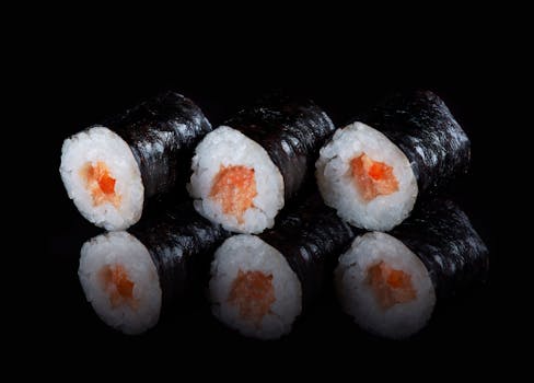 Delicious salmon sushi rolls with reflective black background. Perfect for food lovers.