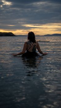 Woman enjoying a peaceful swim at sunset in Rosario Beach, Washington.