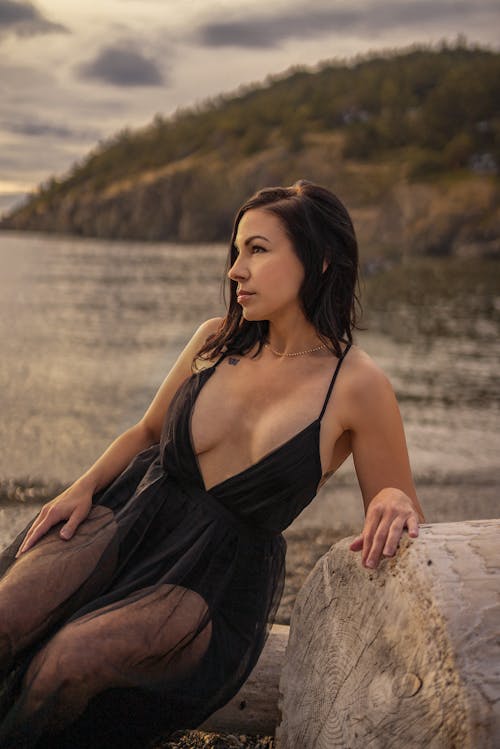 Woman in Lace Dress Sitting Beside a Wood Log