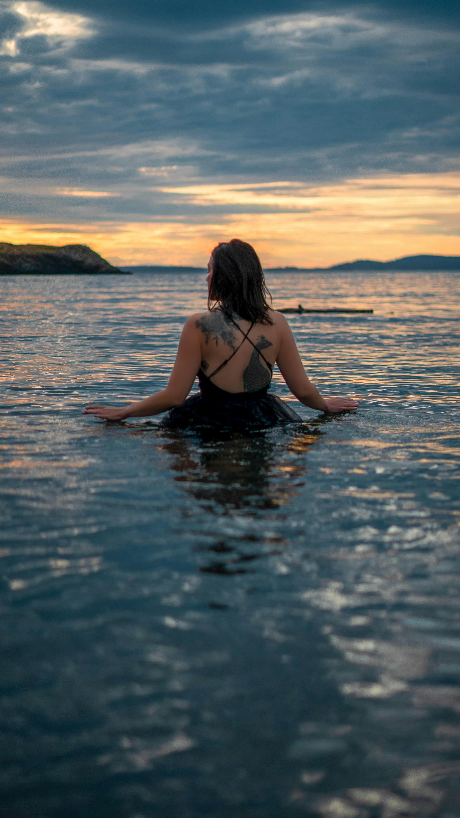 woman in black bikini on water during sunset