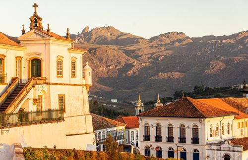 Free Historic colonial buildings in Ouro Preto, Brazil, with a mountainous backdrop during sunset. Stock Photo