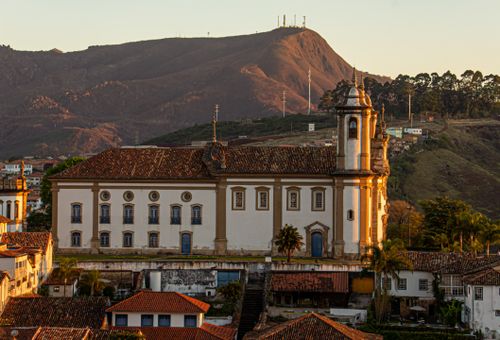 Free Captured at sunset, this image showcases a colonial church in Ouro Preto, Brazil, with mountains in the backdrop. Stock Photo