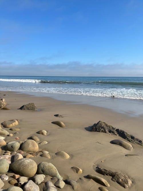 grátis Foto profissional grátis de areia, beira-mar, céu azul claro Foto profissional