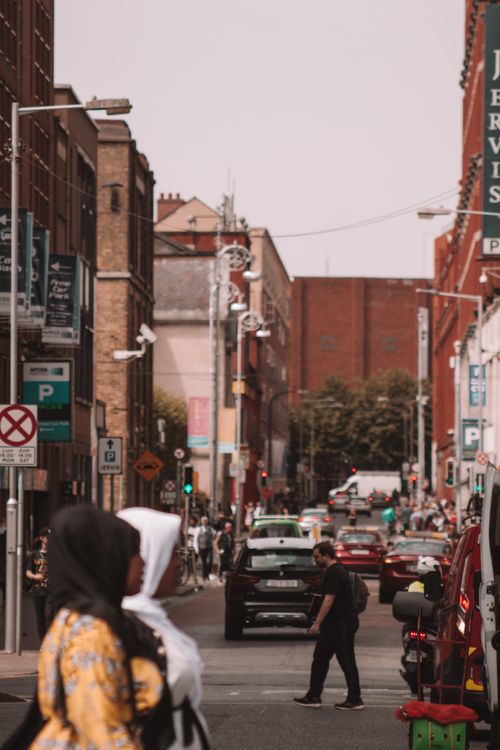 Free Lively city street filled with pedestrians and cars, capturing the essence of urban life. Stock Photo
