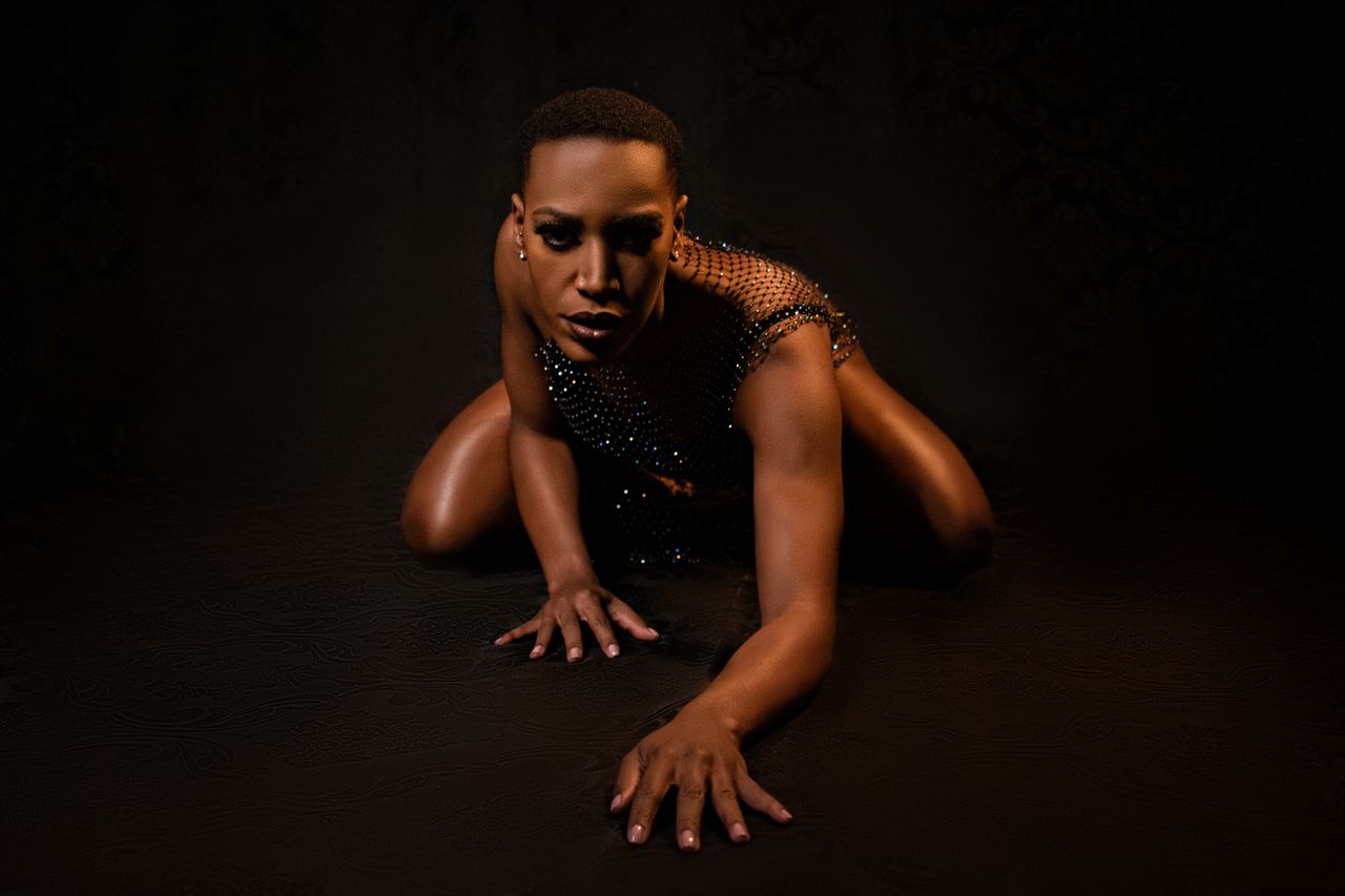 bold portrait of a model in a mesh top posing on a dark background