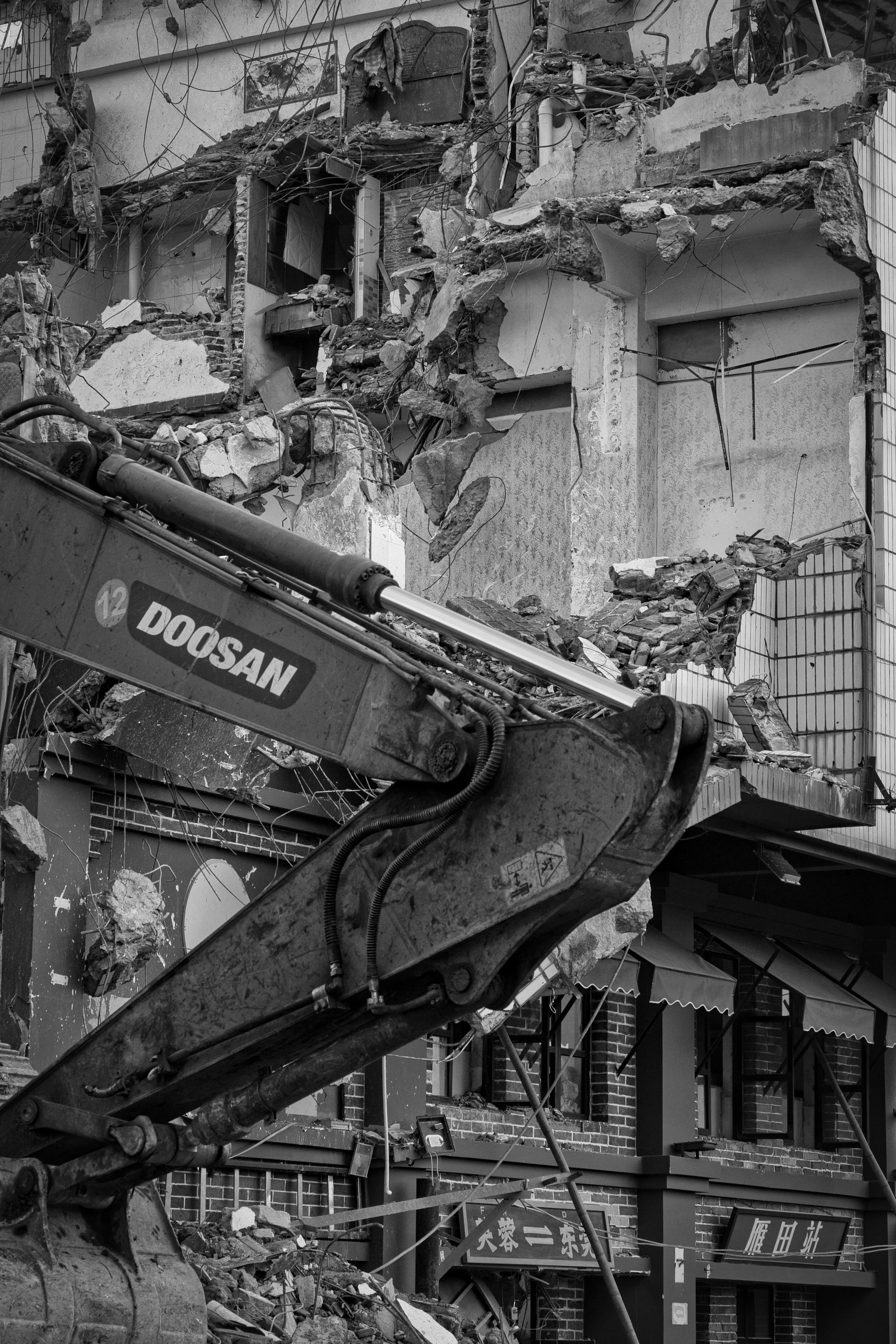 Excavator tearing down urban building, showcasing industrial demolition