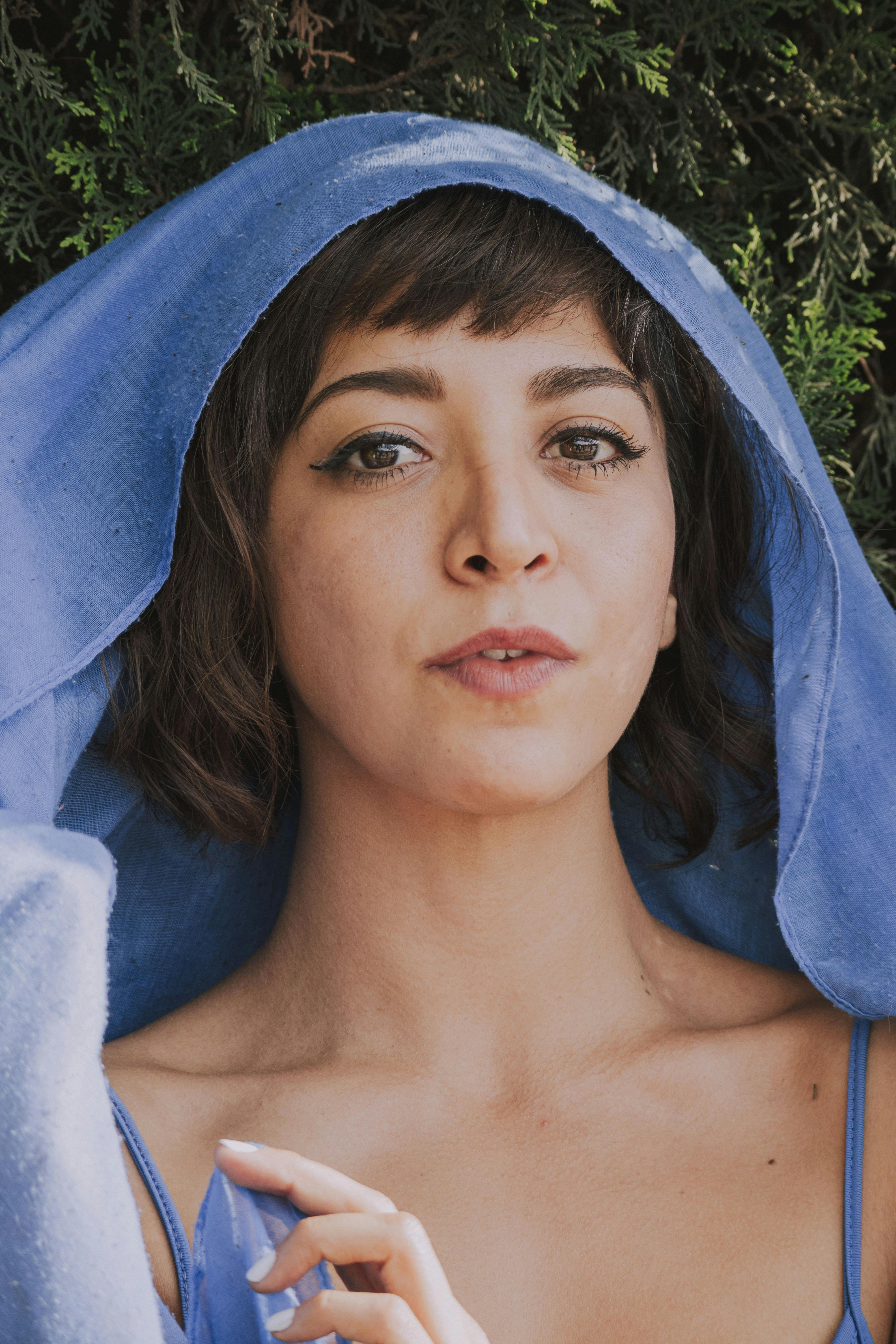 Close-up portrait of a woman in a blue shawl outdoors, showcasing natural beauty and serene expression.
