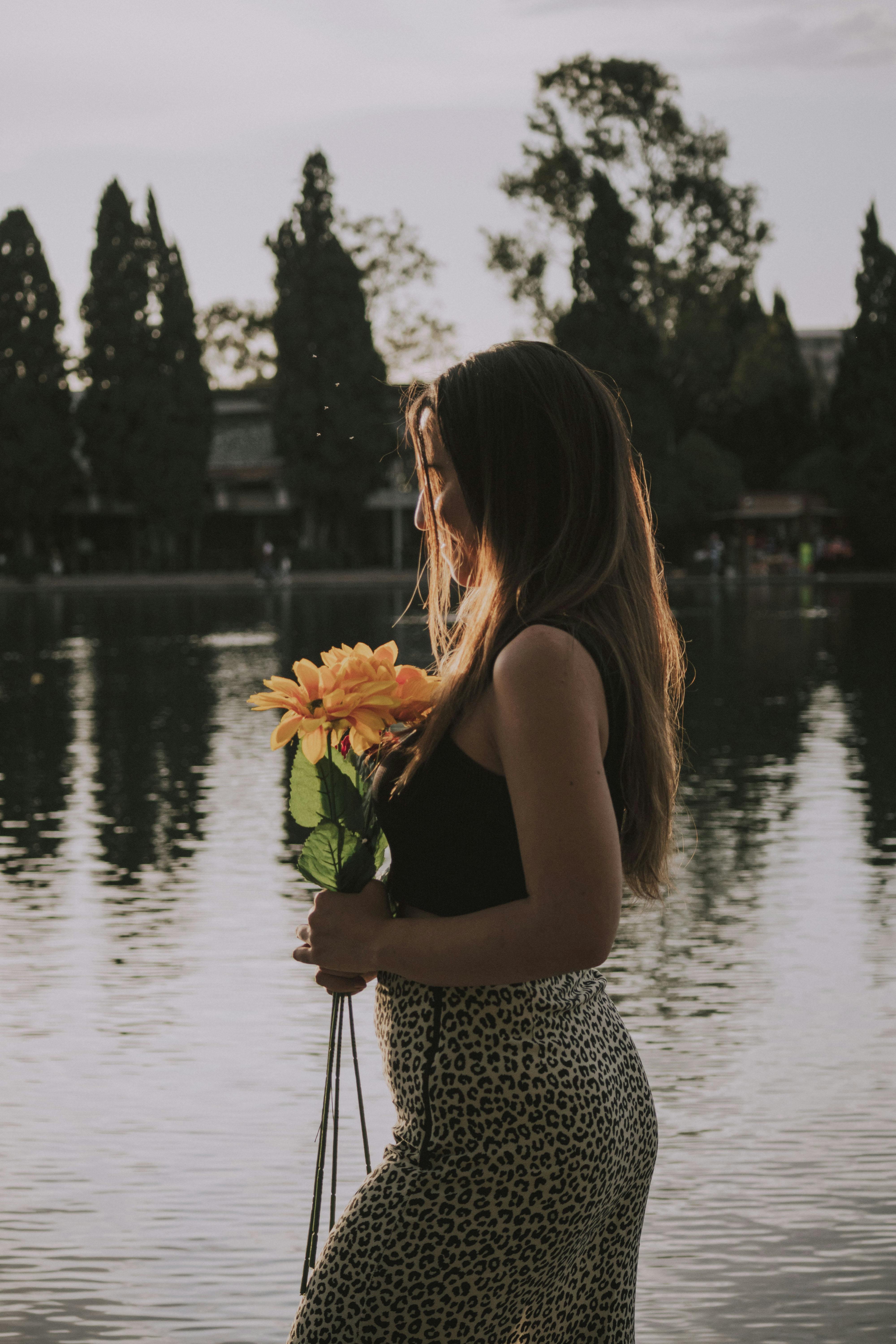 woman by the water holding a bunch of flowers