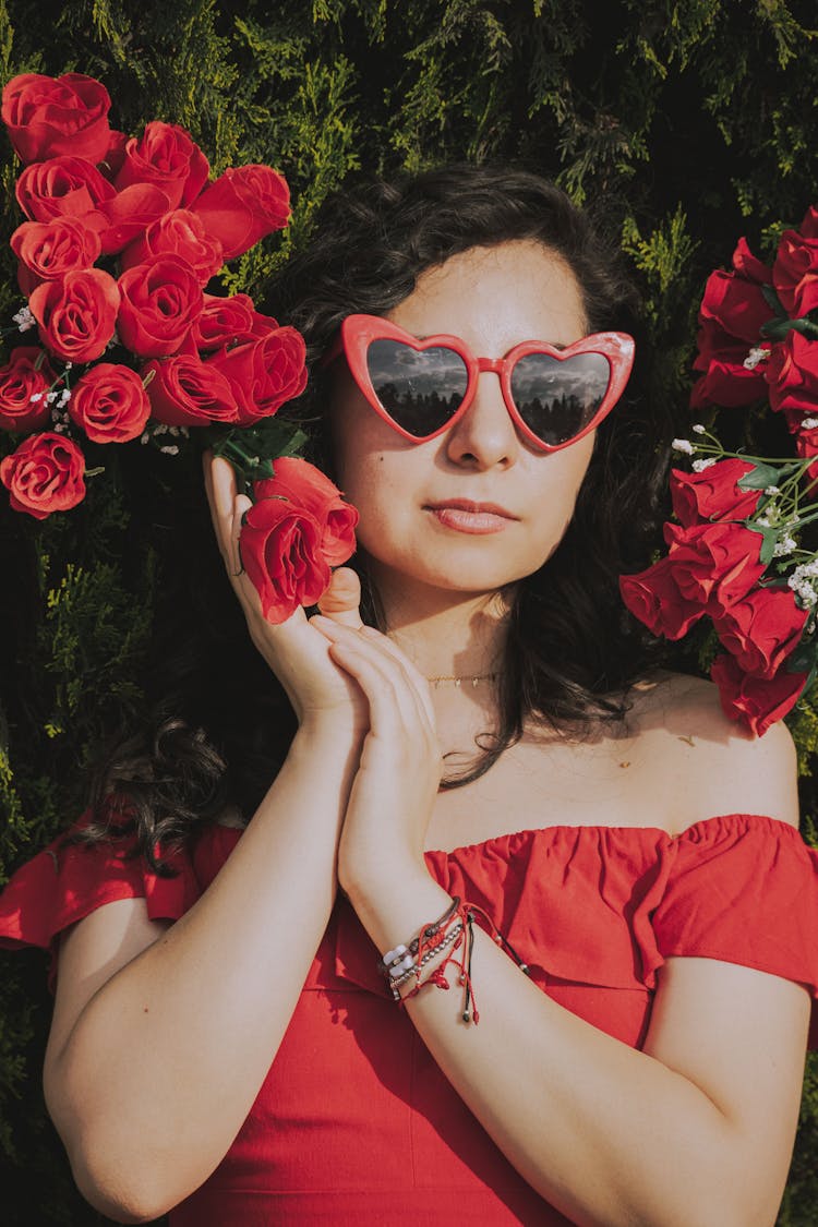 Woman Dressed In Red Standing By Rose Bush