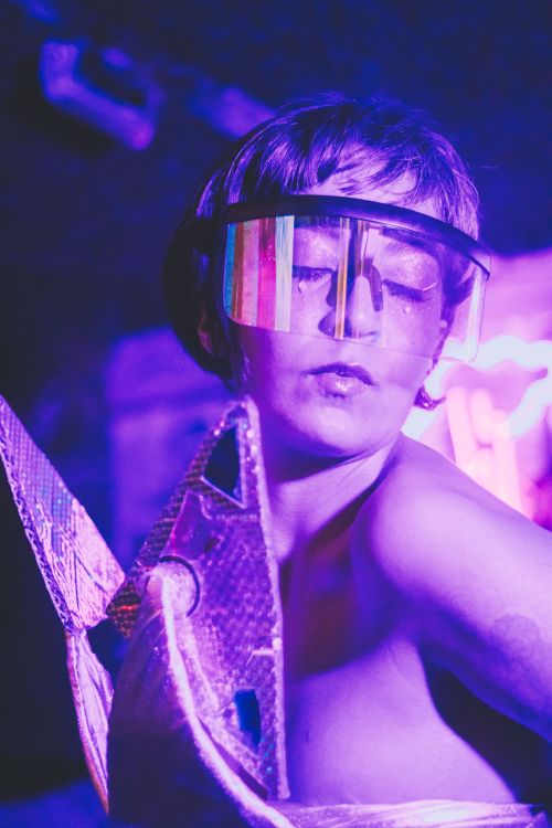 Free Futuristic portrait of a woman in neon lighting wearing reflective visor, showcasing retro futurism style. Stock Photo