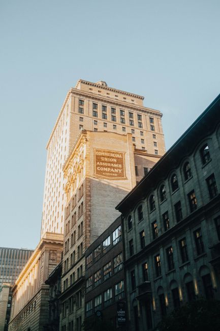 Captured from a low angle, this image showcases the elegant architecture of a historic skyscraper in Montreal.