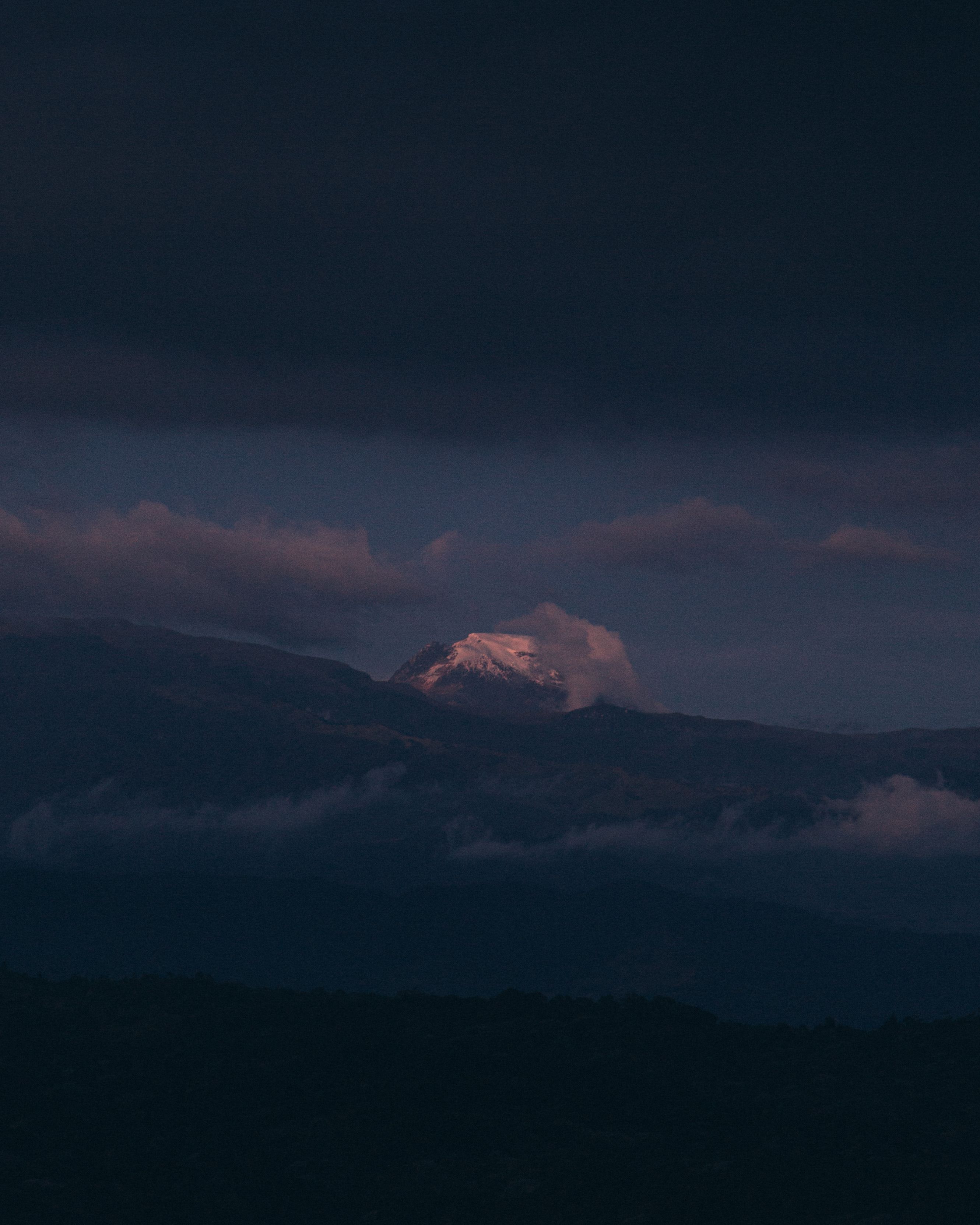 A picturesque mountain peak emerges through clouds at twilight, invoking serenity.