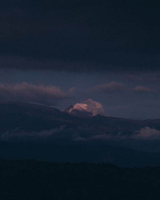 A picturesque mountain peak emerges through clouds at twilight, invoking serenity.