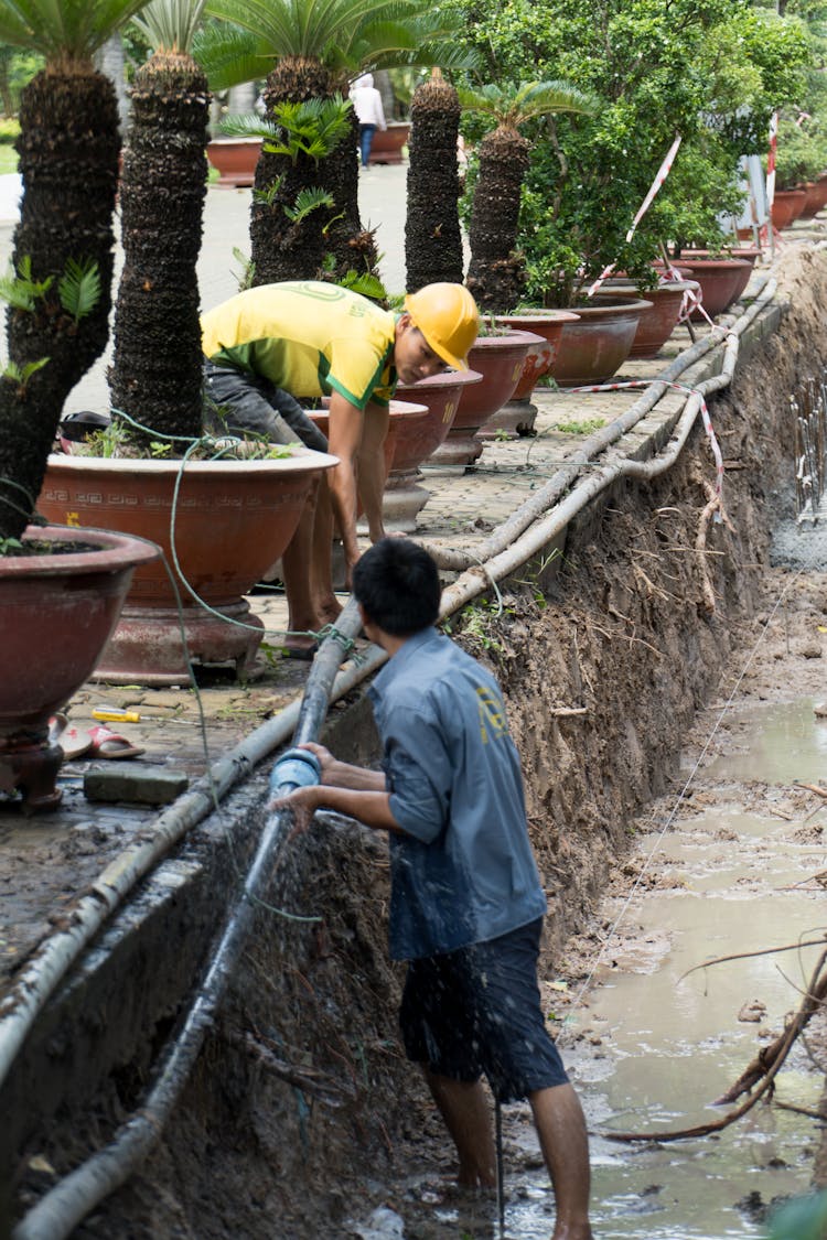 Two Workers Repairing A Pipe