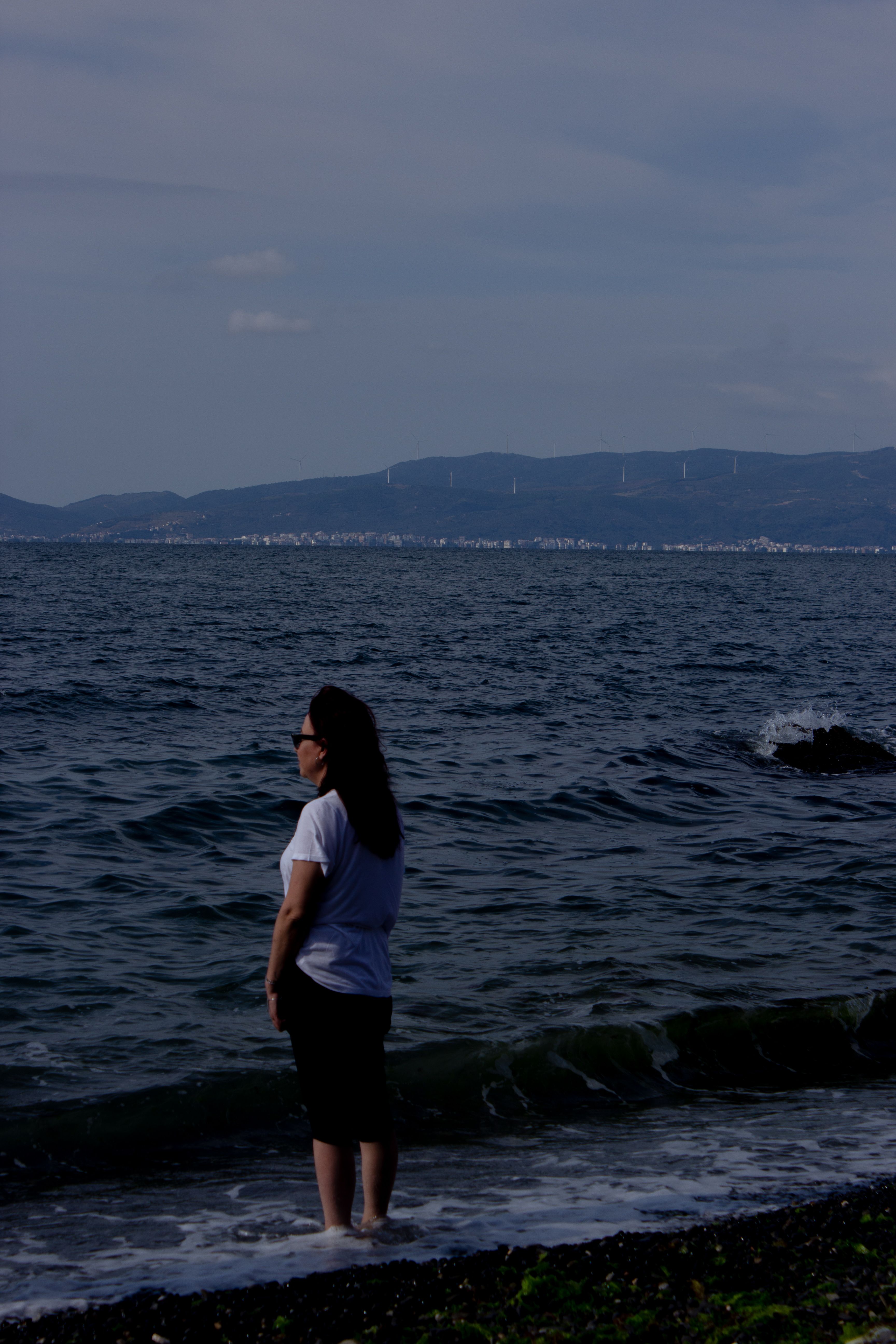 Woman gazing at the tranquil sea in Zeytinbağı, Turkey, creating a peaceful coastal scene.