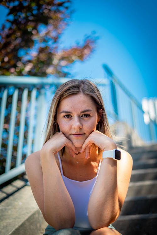 A Woman in White Tank Top with Her Hands on Her Chin