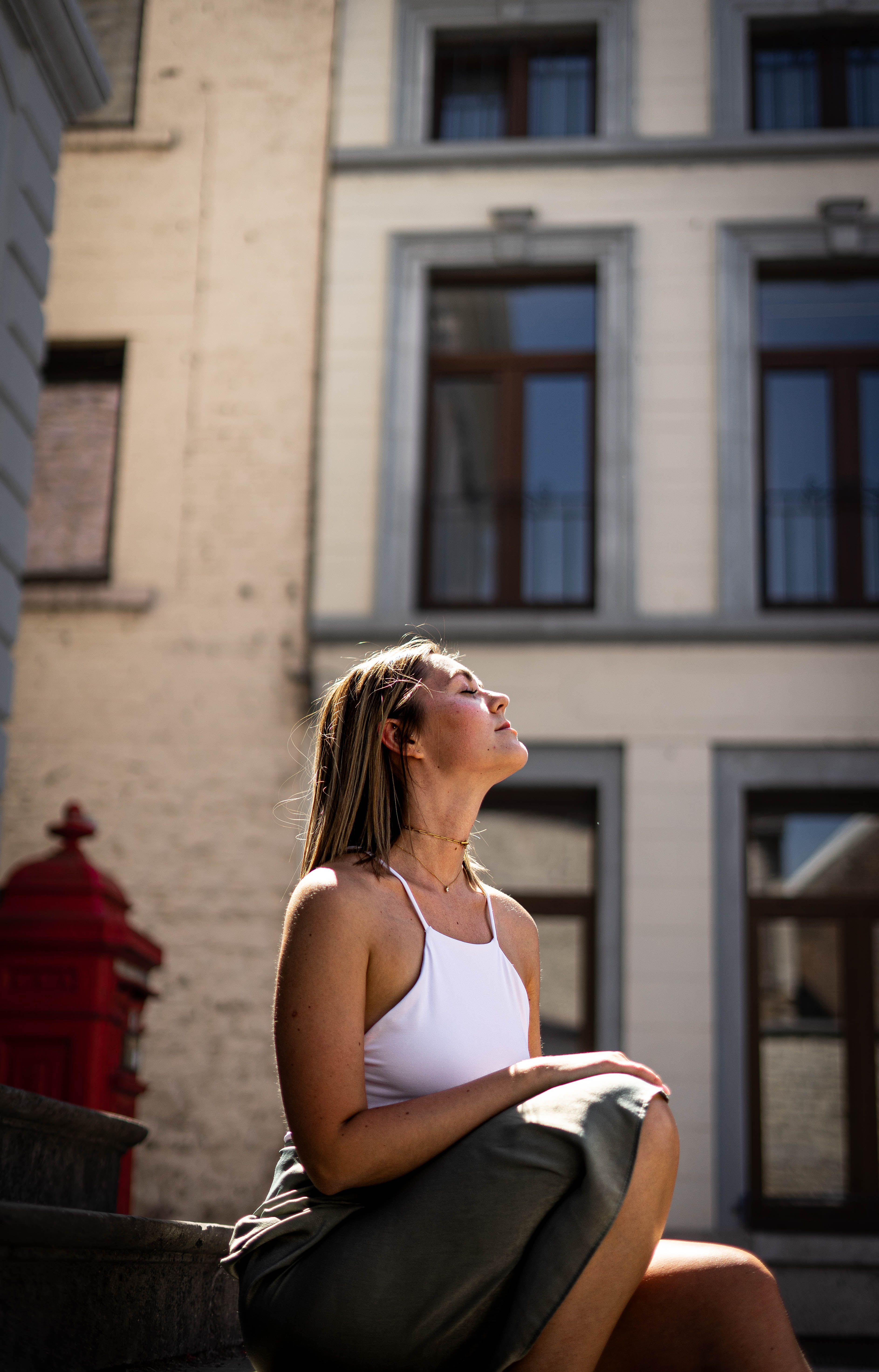 A woman basks in the sunlight on a historic street in Andenne, Belgium.