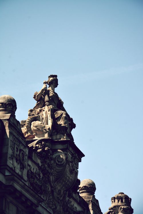 Free Stunning view of a classical sculpture on a Paris rooftop against a clear blue sky. Stock Photo