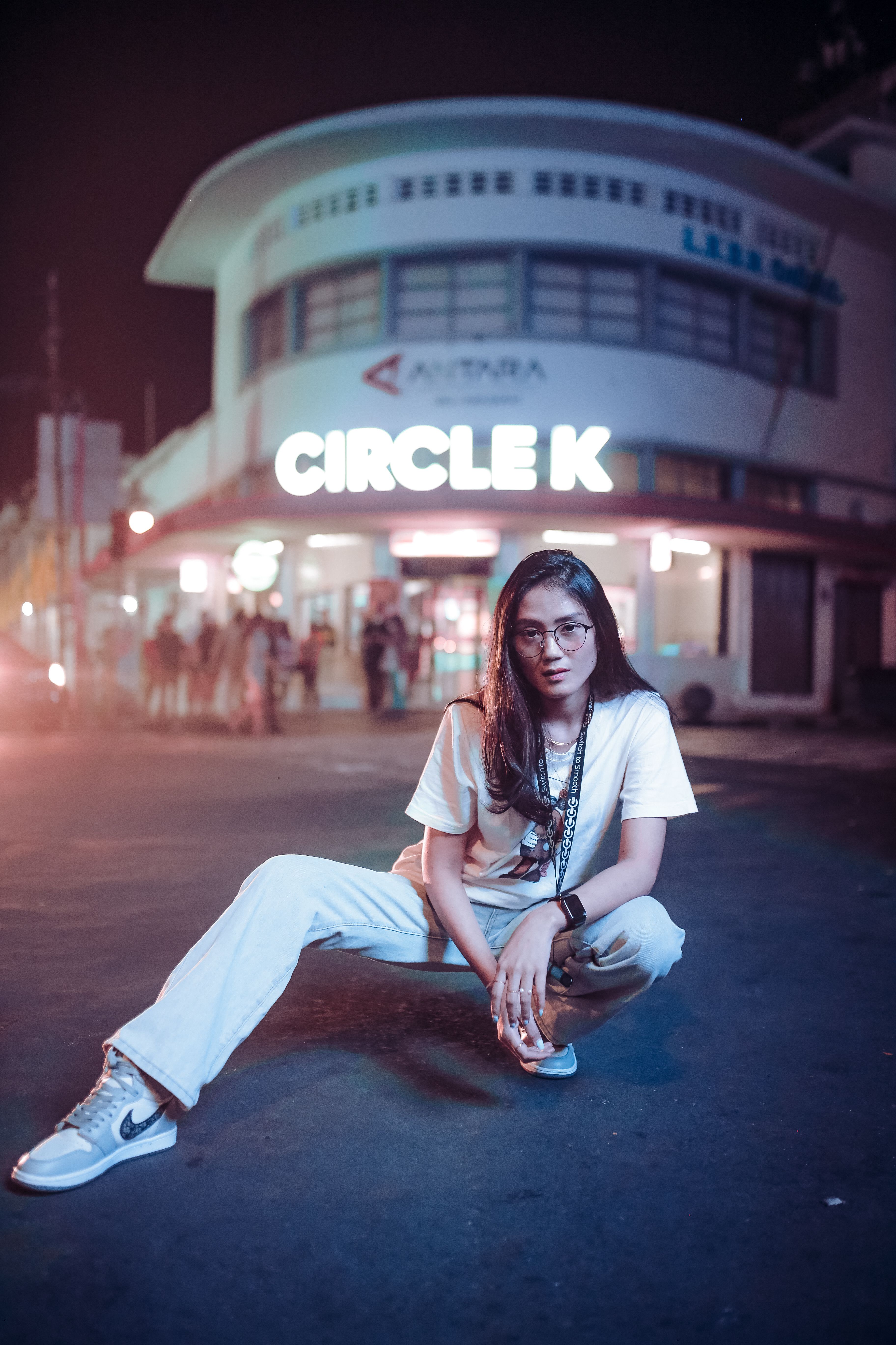 Fashionable woman posing at night in front of a Circle K store in an urban setting.