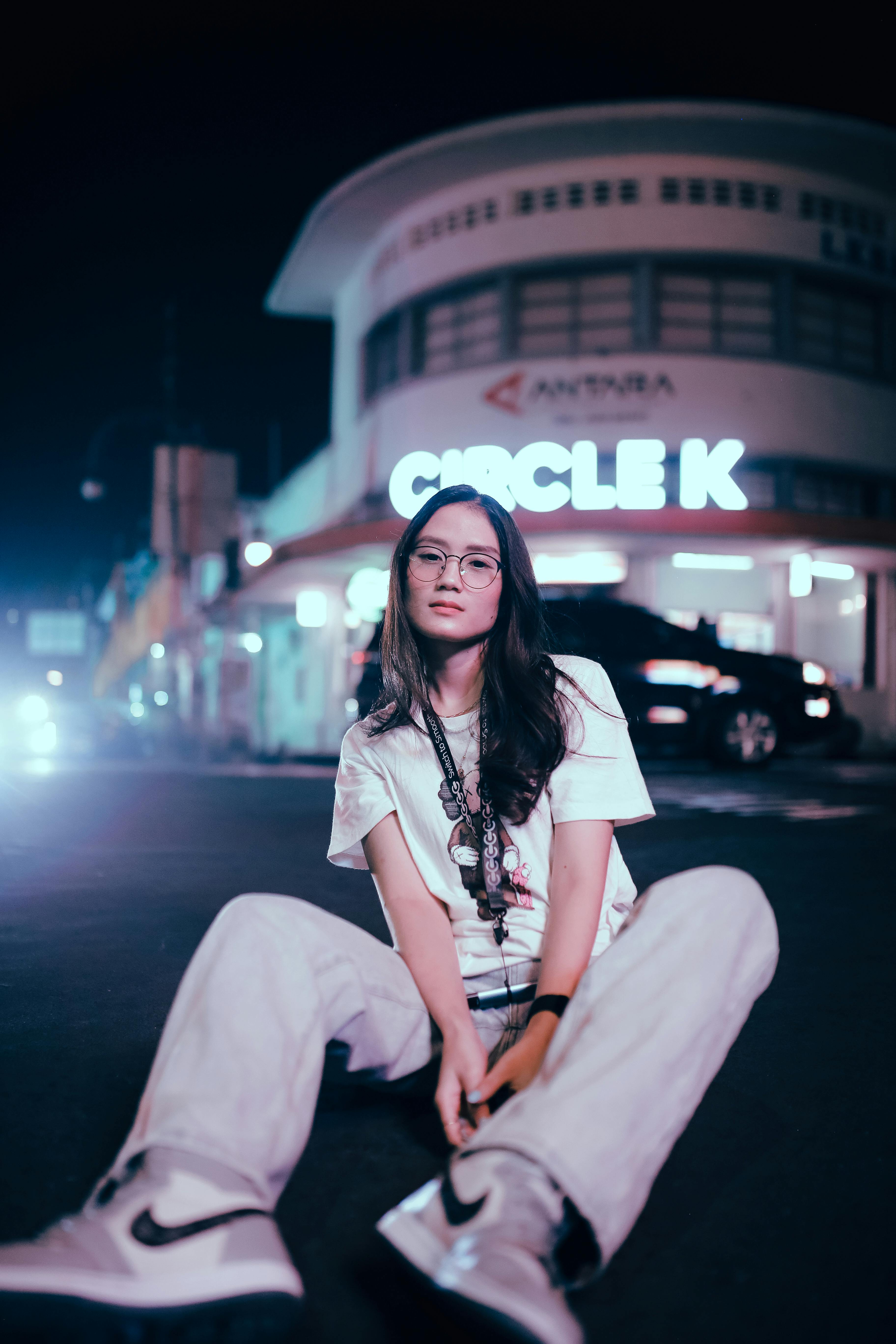 a woman in white shirt sitting on the street