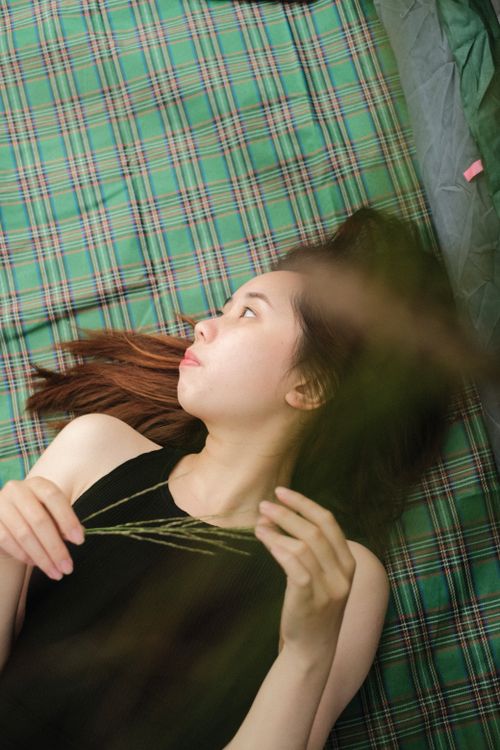 Free A serene image of a young woman lying on a green plaid blanket, enjoying a moment of relaxation. Stock Photo