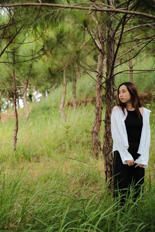 Free Teen girl in forest setting, standing by trees, wearing casual attire and looking contemplative. Stock Photo