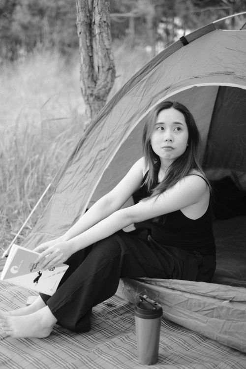 Free A young woman enjoys leisure time reading a book while camping outdoors. Stock Photo