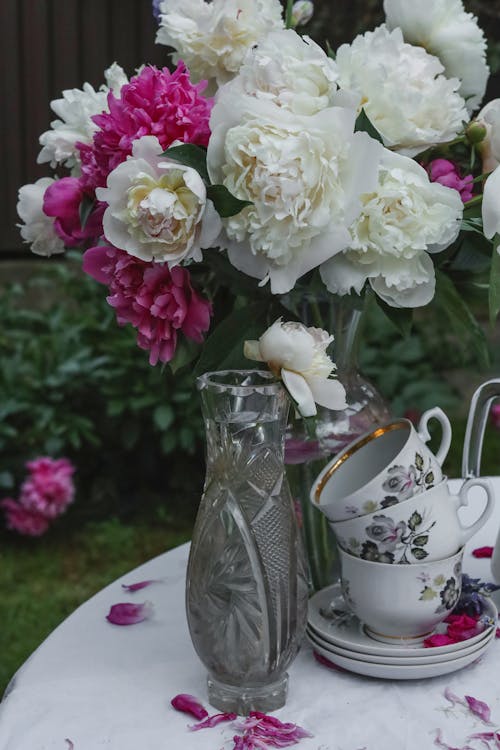 Flowers in a Vase and Tea Cups on a Table in the Garden 