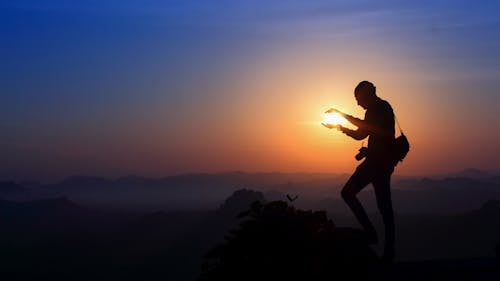 Silhouette of Man Holding Sunset 