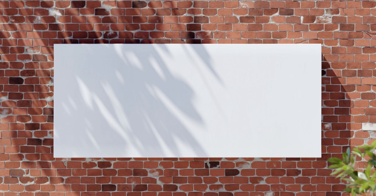 Large blank white banner on a red brick wall with leafy shadows, perfect for mockup designs.