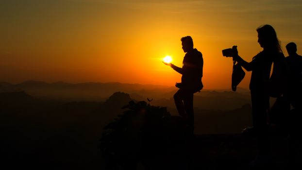 Silhouettes of people capturing a stunning sunset over Hampi's landscape.