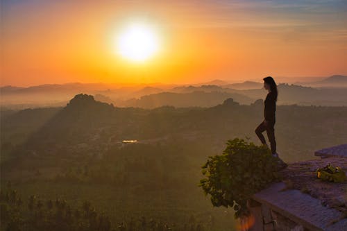 Free Woman Looking at the Scenic View of Foggy Mountains at Sunset Stock Photo