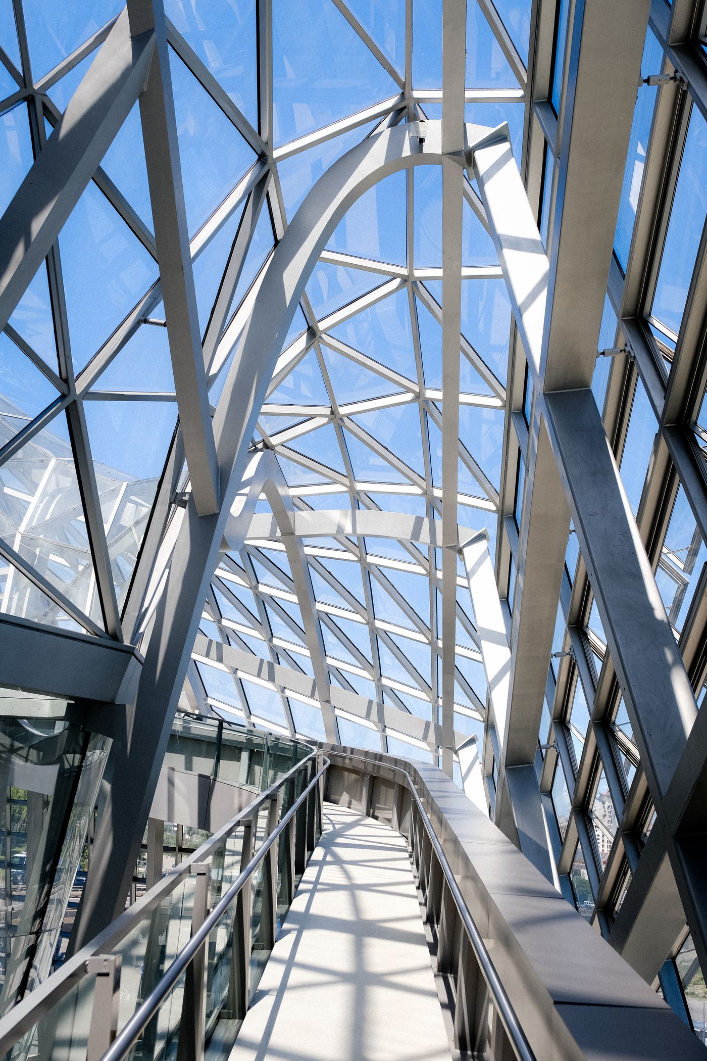 Modern internal ramp with metal handrails beneath a glass roof