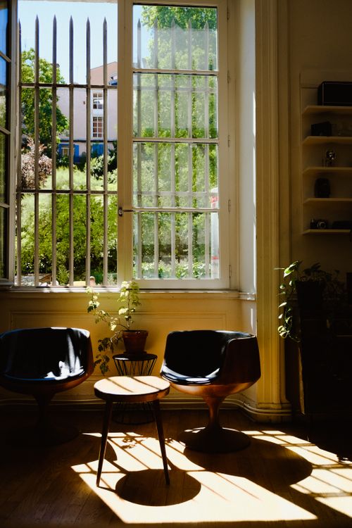 Free Sunlit interior room with stylish chairs, large windows, and outdoor garden view. Stock Photo