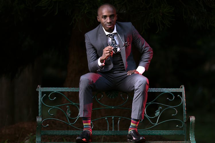 Man In Elegant Suit Sitting On Bench Backrest