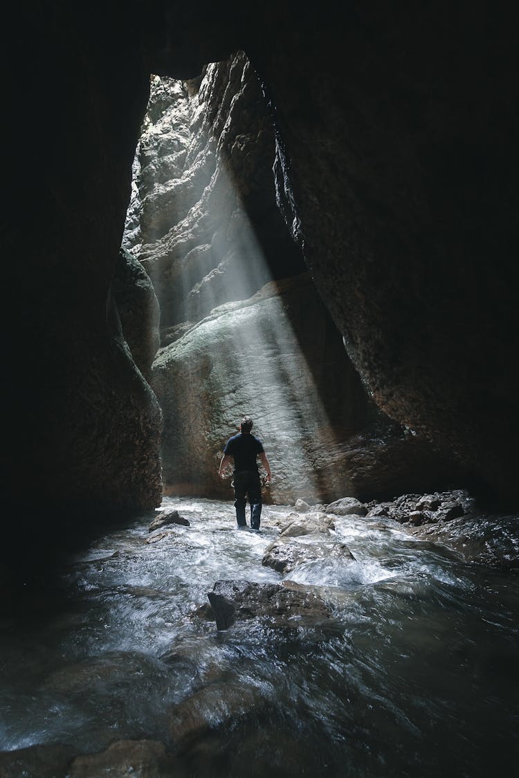 Man Standing In Sunlight In Cave