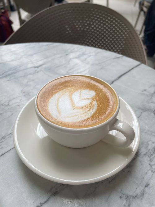 Free Close-up of a cappuccino with latte art served in a ceramic mug on a marble table. Stock Photo