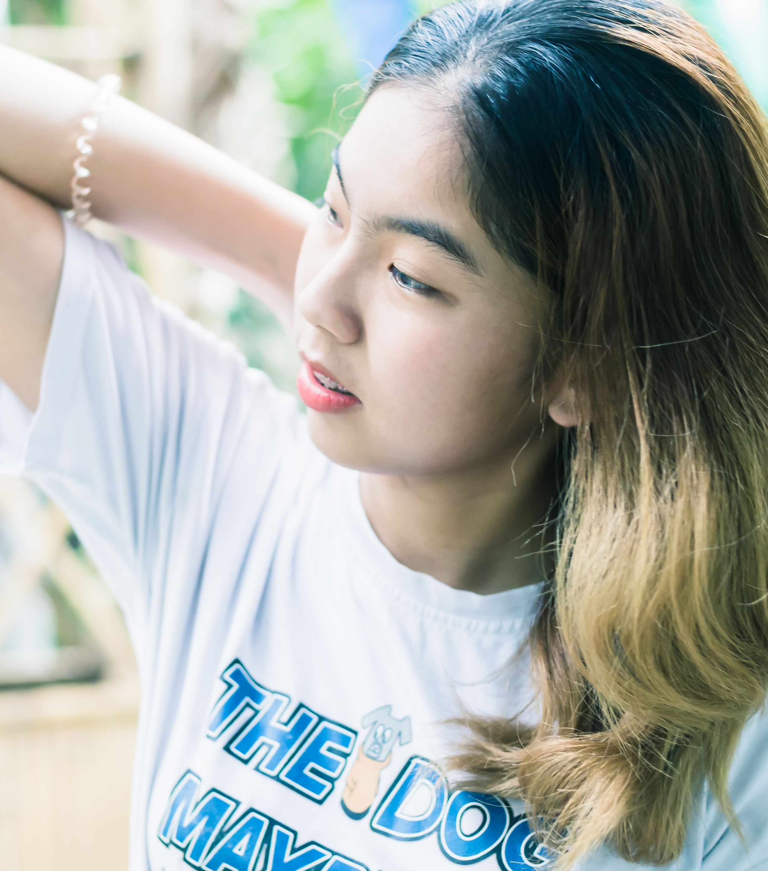 Portrait of a young woman with long hair wearing a white T-shirt, captured outdoors in natural lighting.
