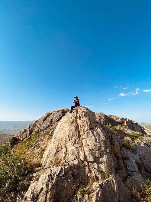 Free Captivating view of an adventurer sitting atop a rocky cliff under a clear blue sky in Ağrı, Turkey. Stock Photo