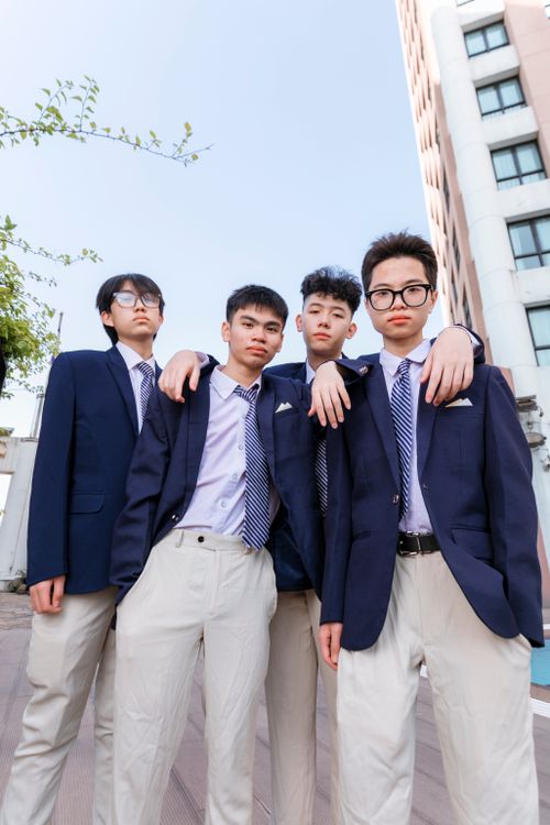 Free A group of four teenage Asian boys wearing formal suits and ties standing outdoors showcasing friendship. Stock Photo