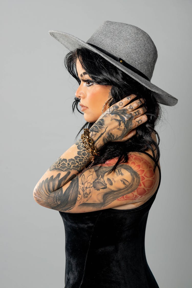 A Woman Wearing Gray Hat With Arms Full Of Tattoo