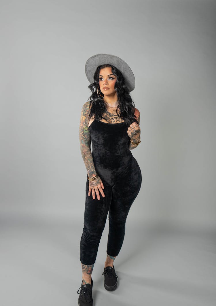 A Woman Wearing Black Jumpsuit And Gray Hat With Arm Tattoo