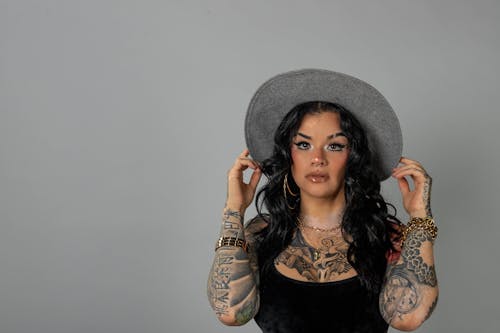 Free Photo of a Woman with Tattoos Wearing a Hat Stock Photo